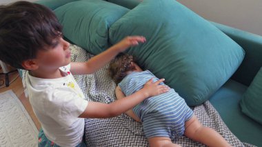 Ağabeyi, çocuklar arasında rahat bir ev ortamında birlikte yatarken, küçük kardeşlerine şakalar yaparak dokunuyor.