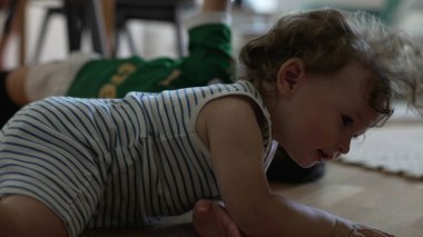 Küçük çocuk evde oyun sırasında yerde yatan ablasının üzerinden tırmanıyor, iki çocuk da evde kendiliğinden bağ kuruyor.