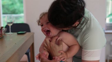 Anne çocuk gibi gıdıklanıyor, çocuk ağzı açık gülüyor. İkisi de evin içinde oynaşmanın ve yakınlaşmanın keyifli anlarını paylaşıyor.