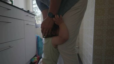 Yeni yürümeye başlayan bir çocuk mutfakta kollarını kaldırmış ve şikayet ifadesini takınarak ebeveyn telefonun yanında dururken alınmak istiyor.