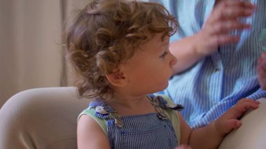 Bebek elinde yaban mersiniyle dolu cam bir kase tutarken ebeveynlerin kucağına oturuyor, ilginç bir şekilde meyve gözlemliyor ve bağımsız olarak yemek yemeyi öğreniyor.