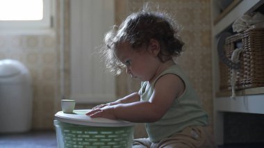 Bebek, mutfak zemininde otururken salata fırıldağı kapağını çevirirken görülmüş. Keşiflerin ilk aşamaları ve kendi kendine başlatılan oyun.