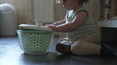 Bebek, mutfak zemininde otururken salata fırıldağı kapağını çevirirken görülmüş. Keşiflerin ilk aşamaları ve kendi kendine başlatılan oyun.