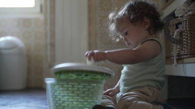 Bebek, mutfak zemininde otururken salata fırıldağı kapağını çevirirken görülmüş. Keşiflerin ilk aşamaları ve kendi kendine başlatılan oyun.