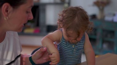 Yemek masasında çatal, dağınık yüz ve odaklanmış ifade ile makarnayı bağımsız olarak yiyen çocuk sıcak aile mutfağında ebeveynin yanında otururken