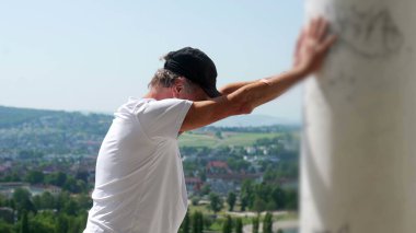 Yaşlı adam kollarını iki kola uzatmış, başını eğmiş, terastan manzarayı seyrediyor rahat ve yansıtıcı duruşuyla.