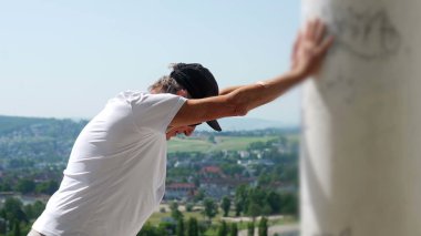 Yaşlı adam kollarını iki kola uzatmış, başını eğmiş, terastan manzarayı seyrediyor rahat ve yansıtıcı duruşuyla.