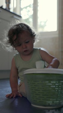 Yürüyen çocuk yerde oynarken kameraya doğru yeşil dönen kaseyi kaldırıyor, oyuncu mutfak aktivitesi sırasında dairesel tasarım ve dokuyu ortaya çıkarıyor