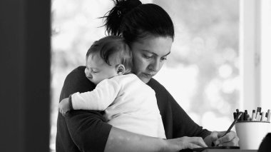Anne, işine odaklanırken bebeğini kucağında tutuyor, bir ofis masasında yazıyor, bakıcılık ve verimliliği sakin bir ortamda dengeliyor, siyah ve beyaz.