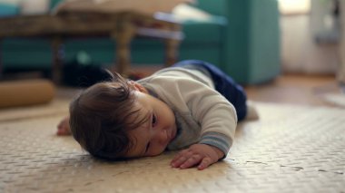 Bebek mindere uzanıyor, baş aşağı dinleniyor, sakin ve rahat, oyun sırasında mola veriyor, rahat konum, ev ortamı, huzurlu ve huzurlu an