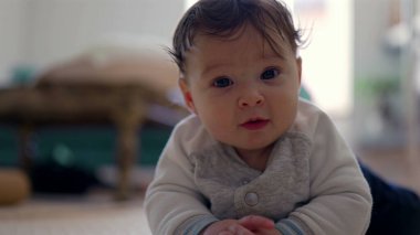 Bebek yan yatmış, başını eğiyor ve gülümsüyor, rahat ve neşeli bir ifade, ev dekorasyonu, erken gelişim aşaması, neşeli ve meraklı bebek içeriyi keşfediyor.