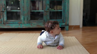 Karnının üstünde bebek, yerde yatarken, erken hareket becerilerini geliştiriyor, başını kaldırıyor, tuhaf bir ifade takınıyor, bebeğin gelişimine odaklanıyor.