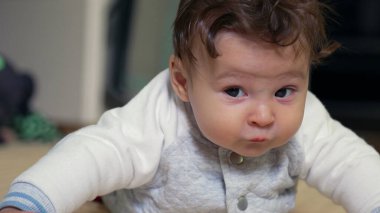 Bebek paspasın üzerinde yatıyor, başı kaldırıyor, ev ortamında erken motor becerileri geliştiriyor.