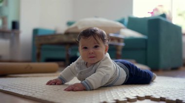 Bebek karnında, üst gövdesini kaldırıyor, kameraya gülümsüyor, oyuncu ve nişanlı, ev dekorasyonu, bebek gelişimi, mutlu bebek keşfi çevresi, meraklı ve özenli