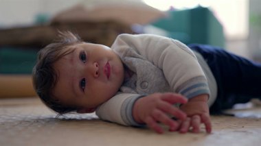Bebek yan yatmış, başını eğiyor ve gülümsüyor, rahat ve neşeli bir ifade, ev dekorasyonu, erken gelişim aşaması, neşeli ve meraklı bebek içeriyi keşfediyor.