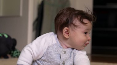 Bebek kollarını kavuşturup yerde uzanıyor. Ev ortamında huzur içinde dinleniyor..