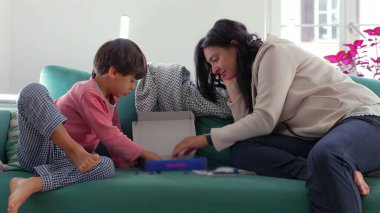 Anne, oğlunun oyuncak uzay gemisini monte edişini izliyor, koltukta birlikte oturuyor, gözlemliyor ve inşaat malzemelerini yerleştirmeye odaklanırken ona destek oluyor.