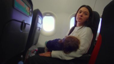 Bakıcı uçak koltuğuna yaslanır ve genç çocuk dinlenir. Yorgunluk anı yaratır. Huzur bağı ve dinginlik ayrılmadan önce.