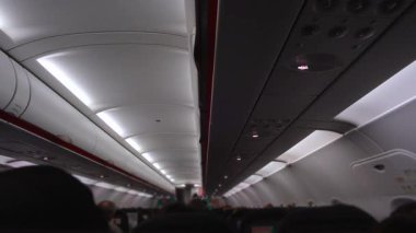 Uçuş sırasında yolcu kabininin iç görünümü oturmakta olan yolcuların sıralarını gösteriyor sessizliği paylaşıyorlar incelikli hareket ve hava yolculuğu deneyimi askıya alınıyor