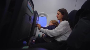 Küçük çocuk uçak tepsisiyle etkileşime girer. Bakıcı, kalkıştan önce keşif anı yaratmayı destekler. Güven duygusu ve erken seyahat deneyimi yaratır.