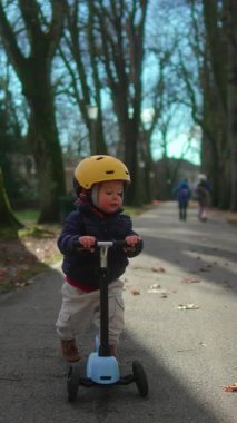 Küçük çocuk uzun ağaçların altında süzülüyor bağımsızlık koordinasyonu merakını ve açık havada aktif aile yaşam tarzını ifade ediyor.