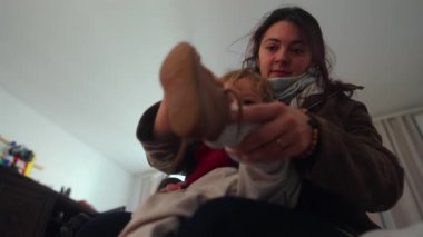Bakıcı ebeveyn evden ayrılmadan önce çocuk ayakkabısını ayarlar. Bu da günlük ebeveynlik ritüeli sırasında güvenlik ve sıcak bağlantıyı yansıtır.