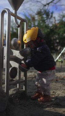 Küçük çocuk açık havada kumlara dokunur ve konsantrasyon koordinasyonu keşfi ve aktif gelişim deneyimini ifade eder.