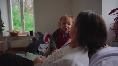 Annem ufaklığın kendini kanepeye atmasını izliyor. Neşeli bir enerji yayıyor, eğlendiriyor. Sıcak bir ortam, nazik bir kaos ve aile içinde sevgi dolu bir bağ.