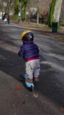 Küçük çocuk kaldırımlı patikada süzülüyor. Etrafı ağaçlarla çevrili. Bu da güven koordinasyonunu ve dışarıda sağlıklı bir aile yaşantısını yansıtıyor.