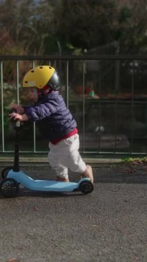 Küçük çocuk, demir parmaklıkların yanında scooter sürüyor. Su kenarındaki parmaklıklar bağımsızlığını ve şehir doğasında sağlıklı bir aile yaşantısını ifade ediyor.