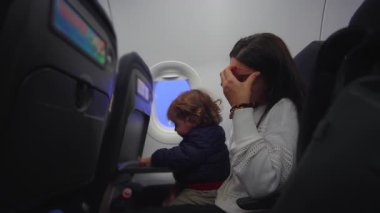 Bakıcı el ele dinlenirken, küçük çocuk uçuş öncesi uçak koltuğunu keşfediyor. Bekliyor ve dürüst bir ebeveyn olma zamanı yaratıyor. Dayanıklılık ve ortak yolculuk.