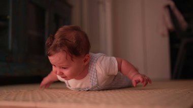 Bebek karın boşluğunda aşağı bakıyor, hareket ve çevreyi keşfetmeye odaklanıyor, erken gelişim kilometre taşı, rahat ev ortamında doğal oyun