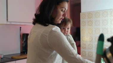 Anne ebeveynliği dengelemek ve mutfakta çoklu görev yapmak, günlük ev işlerini organize ederken ve yönetirken bebeği tutmak, aile hayatı ve bakım üzerine odaklanmak