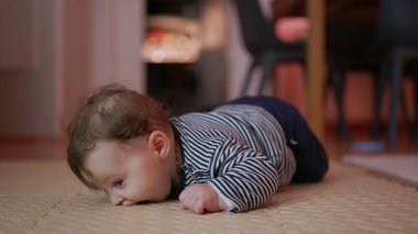 Bebek mindere uzanıyor, kollara dayanıyor, garip ifade, çevreyi keşfetme, gelişim göbeği aktivitesi, ev içi ortam, erken motor becerilere odaklanıyor.