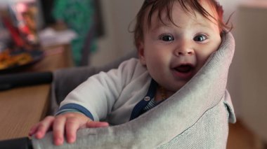 Bebek sevinçle gülerken minderli sandalyeye yaslanıyor, saf mutluluk, geniş gülümseme, neşeli ifade, neşeli enerji, çocukluk sevincinin doğal anı