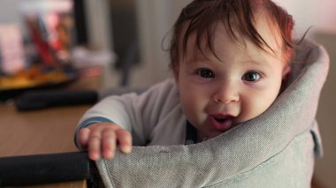Bebek sevinçle gülerken minderli sandalyeye yaslanıyor, saf mutluluk, geniş gülümseme, neşeli ifade, neşeli enerji, çocukluk sevincinin doğal anı
