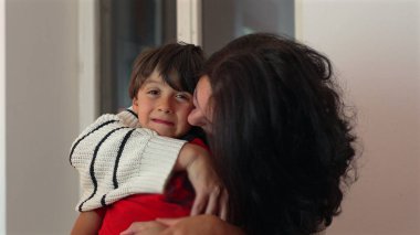 Anne oğul yanağı, içten sevgi ve yakınlık anı, neşeli ifadeli çocuk, güçlü bir aile bağı ve sıcak bir iç mekanda sevgi dolu bir bağ.