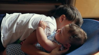 Küçük çocuk uzanmış, bebek kardeşi kucaklıyor, sevgi dolu kardeş bağı, samimiyet ve sevgi, nazik aile anı, çocukluk bağı, yakın ve hassas etkileşim