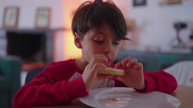 Yemekte bir çocuğun hamburgeri ısırmasını yakından görmek, açlık, bağımsızlık ve basit konforlu yemek keyfi ifade eden doğal evcil sahne