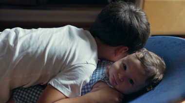 Küçük çocuk uzanmış, bebek kardeşi kucaklıyor, sevgi dolu kardeş bağı, samimiyet ve sevgi, nazik aile anı, çocukluk bağı, yakın ve hassas etkileşim