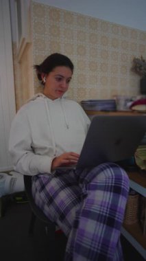 Bilgisayarda yazan profesyonel bir kadın mutfak ortamında bacakları dengeli, kapalı alanda üretkenliği, esnekliği ve günlük çevrimiçi iş rutinini aktaran gizli bir sahne