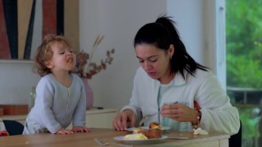 Genç anne, çocuğuna kahvaltı sırasında rehberlik etmek, güven bağı kurmak ve ilişki geliştirmek için evde bebekle keyifli yemek saatleri paylaşıyor.