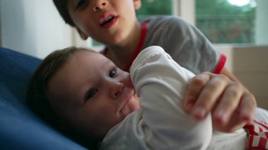 Ağabeyi bebeği kucaklıyor, hassas kardeş bağı, koruyucu jest, çocukluk arkadaşlığı, sevgi, ilgi, bağ, yakınlık, aile sıcaklığı, yuva kurma