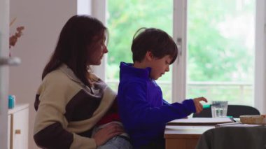 Çocuk istirahatı ve okul desteğini dengeleyen ebeveyn, oğlunun not defterine yazdığı gibi, aile sahnesinde sorumluluk ve günlük yaşantısını ifade ediyor.