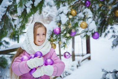 Güzel kız pembe ceket ve beyaz kaşkollu Noel ağacı arka plan üzerinde bir kucak dolusu Noel topları tutan