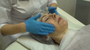 Eller güzellik uzmanı bir kadının yüzünde krem sürün