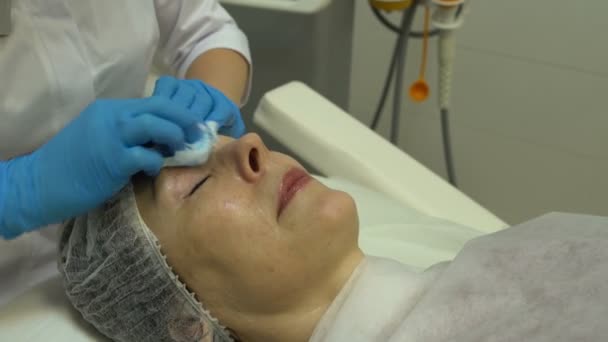 美容師は、女性の顔から余分なクリームを削除します — ストック動画
