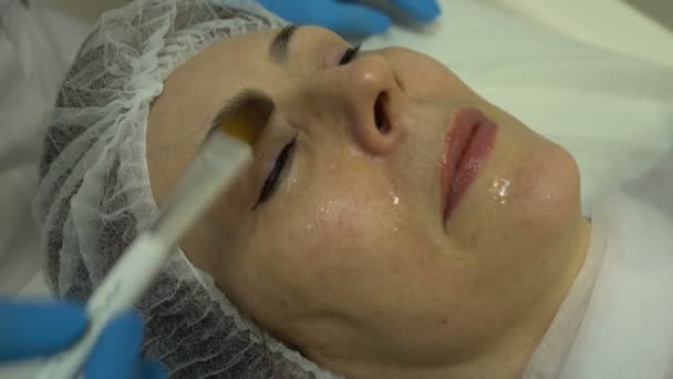 Esteticista extiende cepillo de crema en la cara de las mujeres — Vídeos de Stock