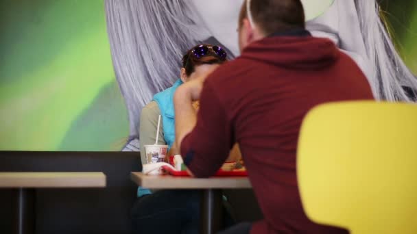 Een man en vrouw eten hamburgers — Stockvideo