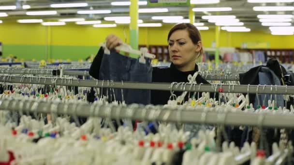 En kvinna väljer en jeans butik — Stockvideo
